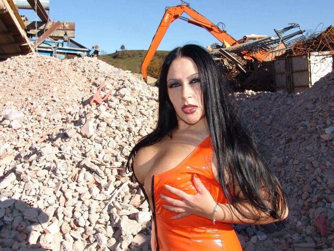 16P Mulher vestida perde seus peitos grandes com um vestido de látex perto de equipamentos pesados