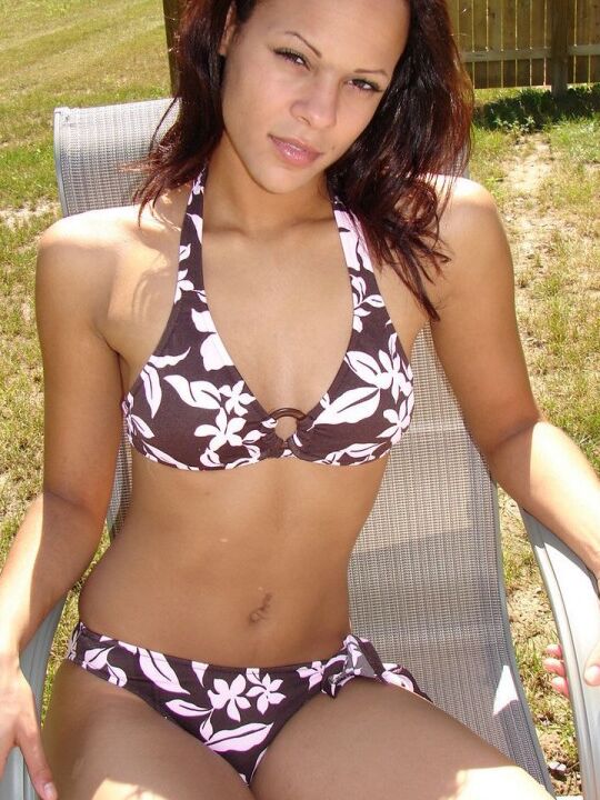 12P La joven amateur Karen modela un bikini con estampado floral en una silla del patio trasero