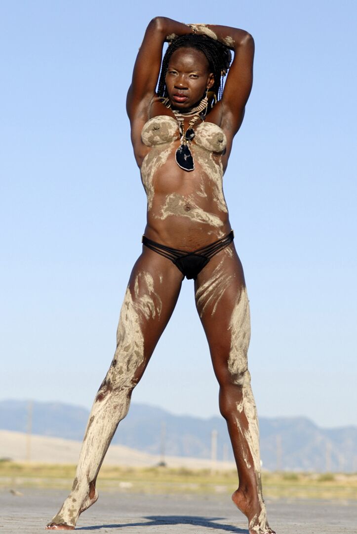 Camille Elizabeth, bodybuilder ébène de 15P, couvre son corps tonique dans le sable de la plage.