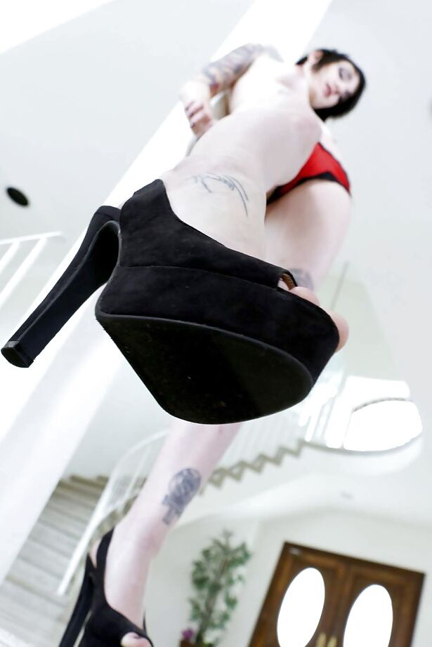 16P La estrella porno morena tatuada Nikki Hearst posando con tacones altos