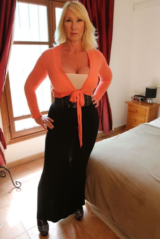 20P Sexy ältere Blondine Melody zieht ihren BH und langen Rock in High Heels auf dem Bett aus