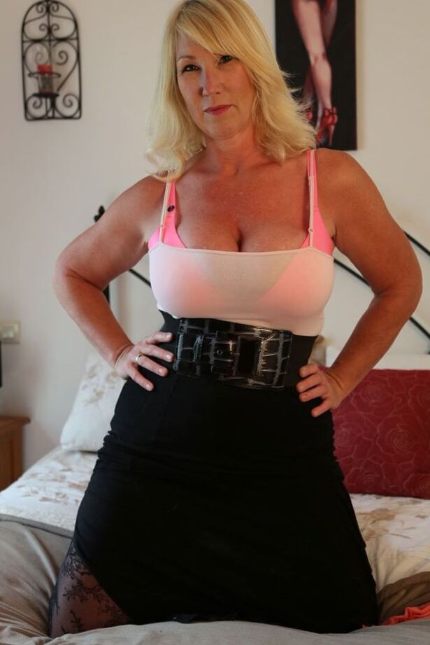 20P Sexy ältere Blondine Melody zieht ihren BH und langen Rock in High Heels auf dem Bett aus