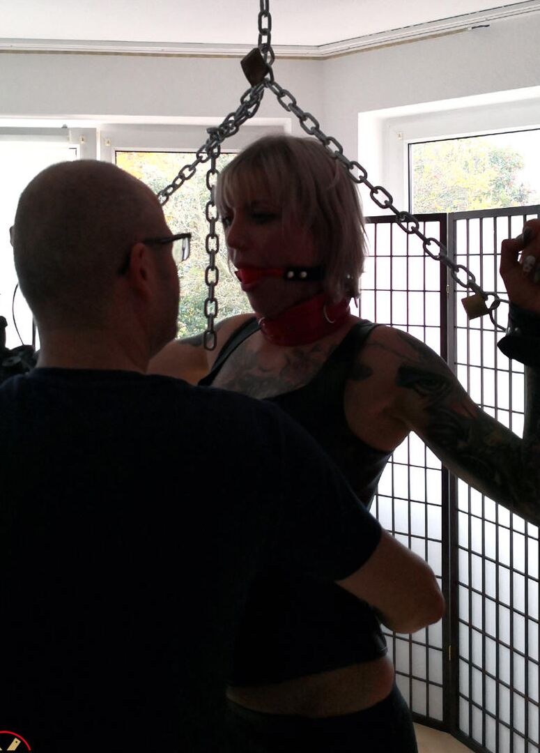 15P Tattooed blonde Roxxxi Manson is fitted with a ball gag while chained