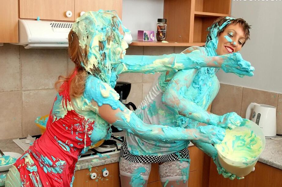 16P Mulheres vestidas se cobrem com mistura de bolo durante uma briga de comida na cozinha