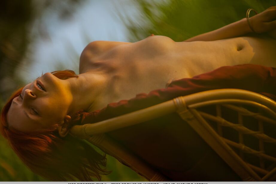 16P Natural redhead Andrea P models totally naked on a chair near the water