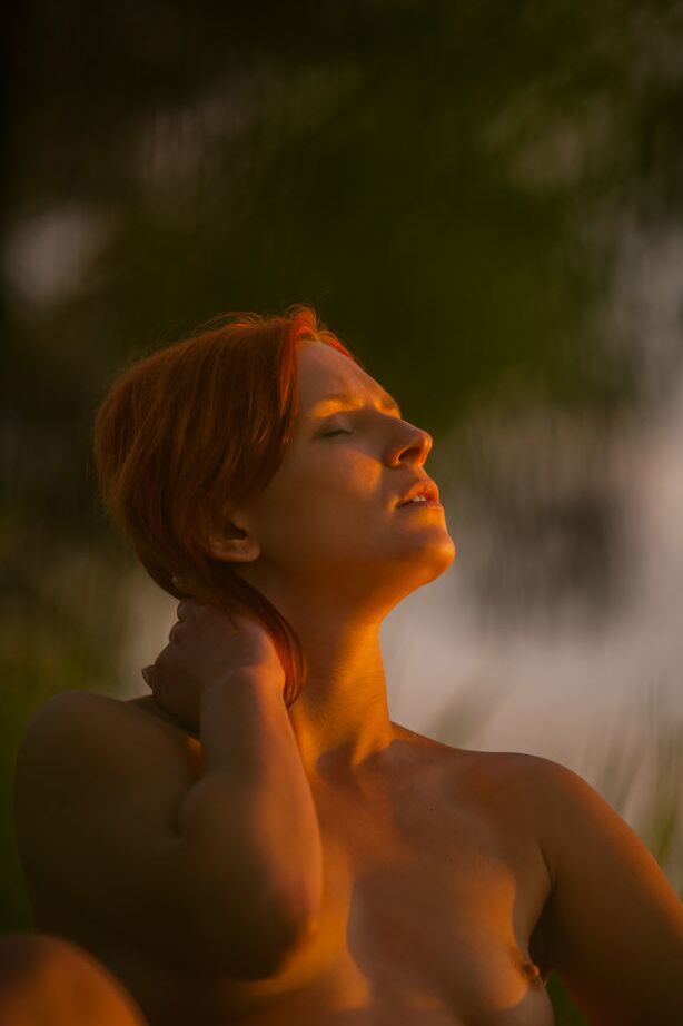 16P Natural redhead Andrea P models totally naked on a chair near the water