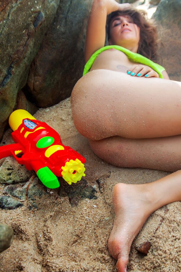 Das 16-jährige Solo-Mädchen Bori Keis schwingt eine Wasserpistole, während sie sich am Strand auszieht