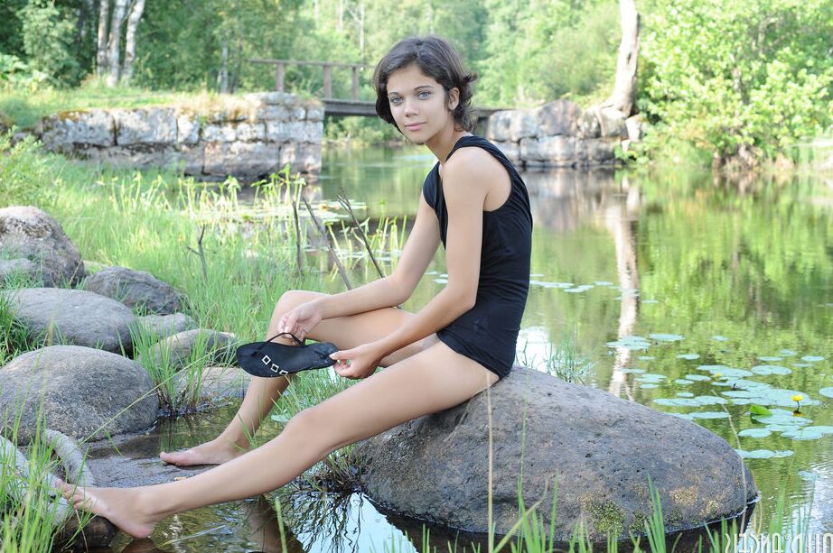 20P Young brunette shows her tight slit in the nude on rock by a pond