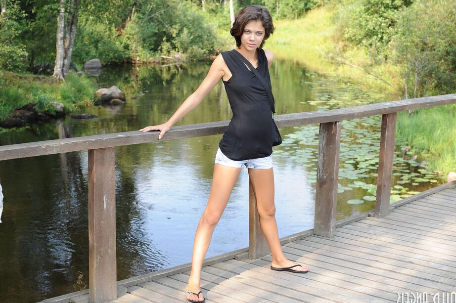 20P Young brunette shows her tight slit in the nude on rock by a pond