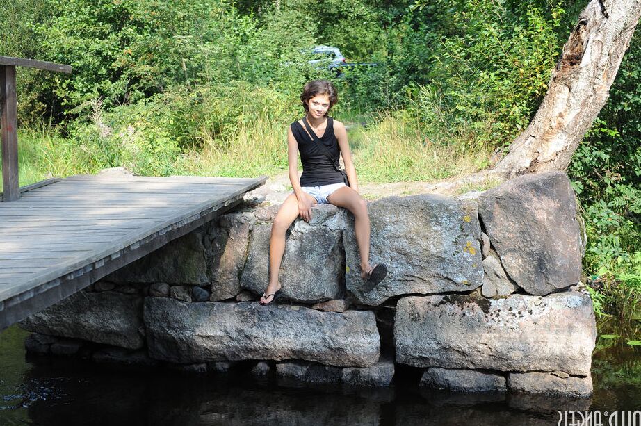 20P Young brunette shows her tight slit in the nude on rock by a pond