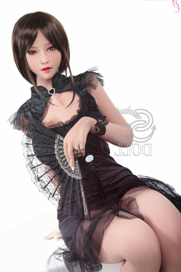 21P Une poupée sexuelle brune dans une robe noire chaude montre sa chatte et ses gros seins