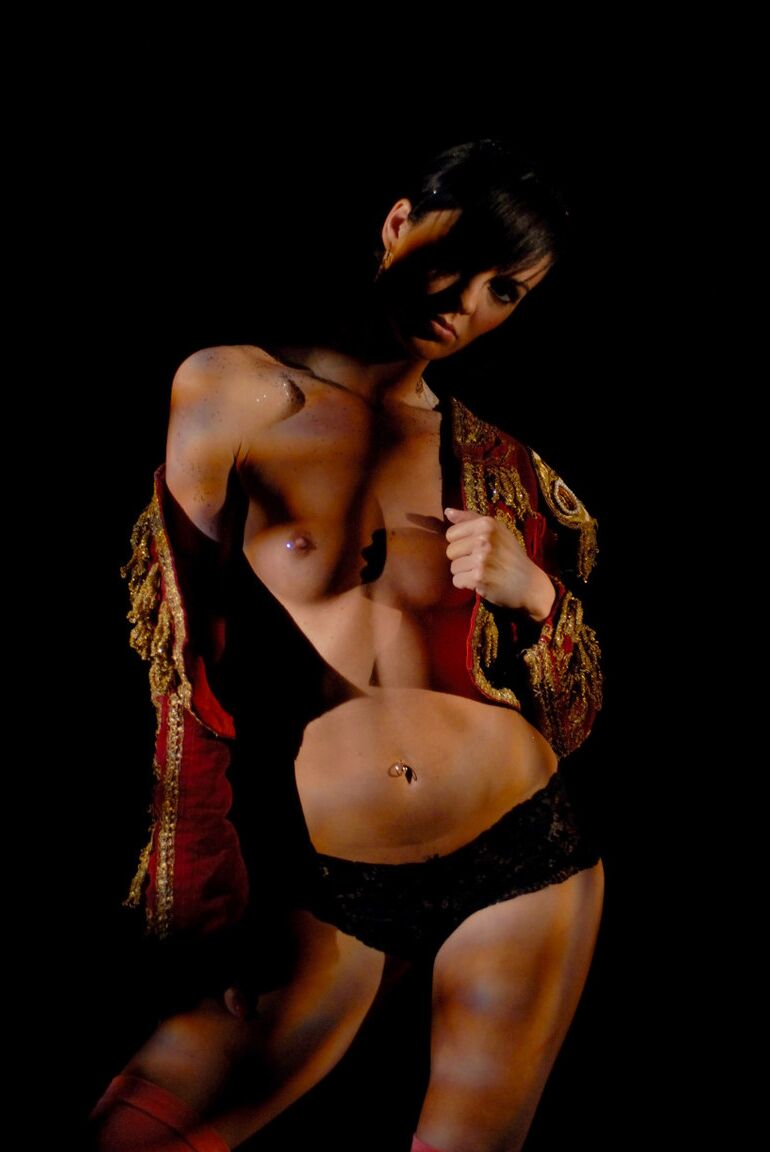 16P Une fille solo nue aux cheveux noirs courts enfile une tenue de matador dans le noir