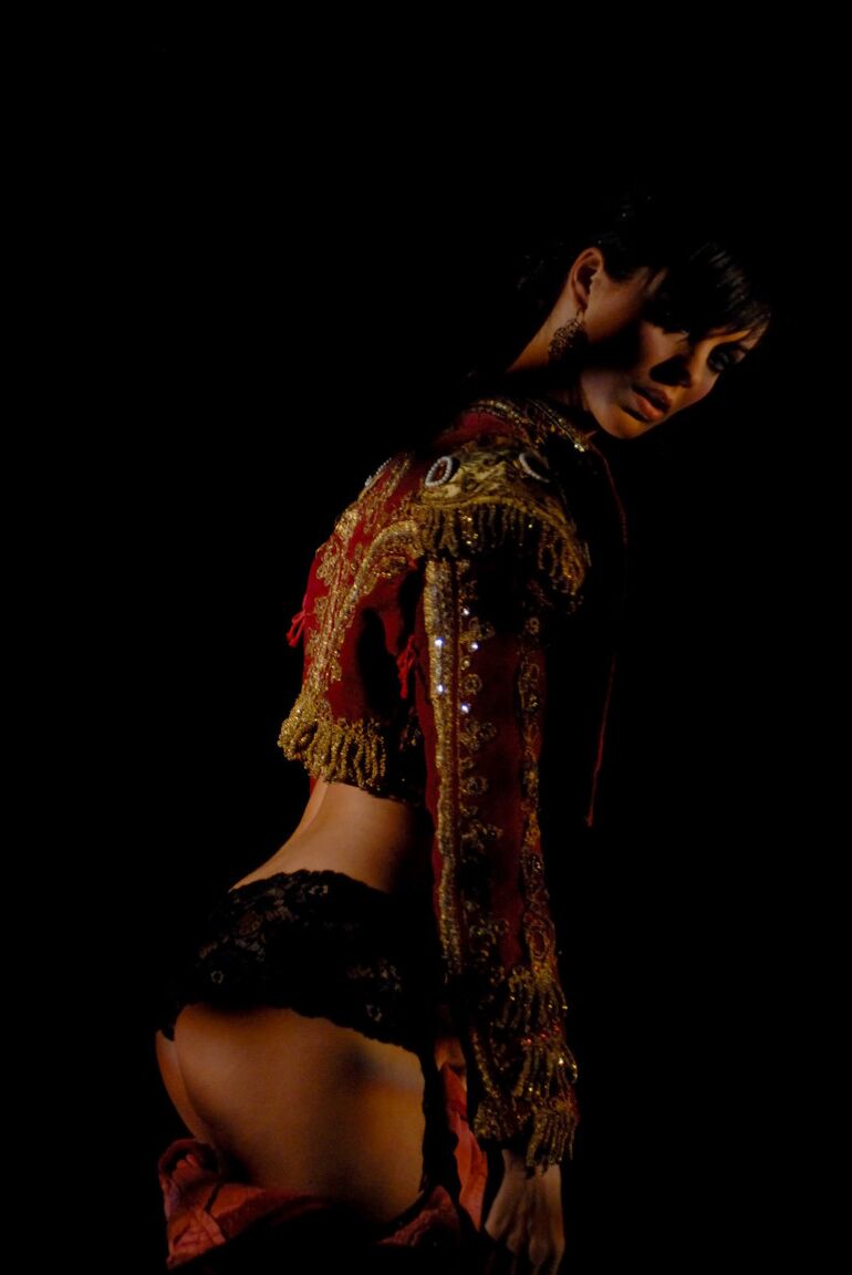 16P Une fille solo nue aux cheveux noirs courts enfile une tenue de matador dans le noir
