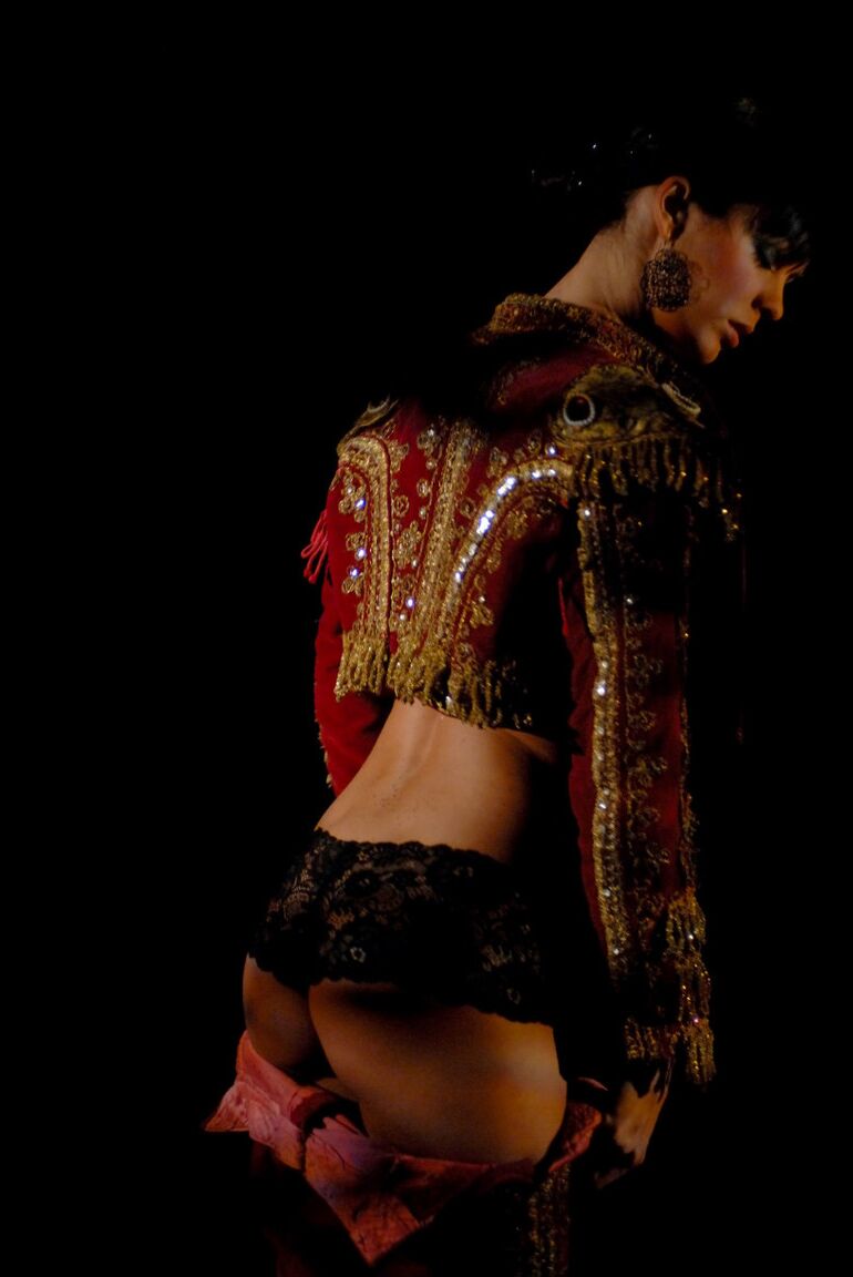 16P Une fille solo nue aux cheveux noirs courts enfile une tenue de matador dans le noir