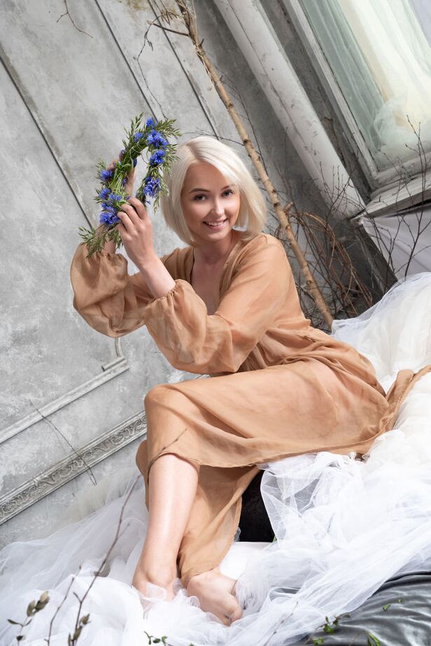Bernie, une adolescente blonde platine 18P, enlève une couronne de fleurs lors d'une séance de nu