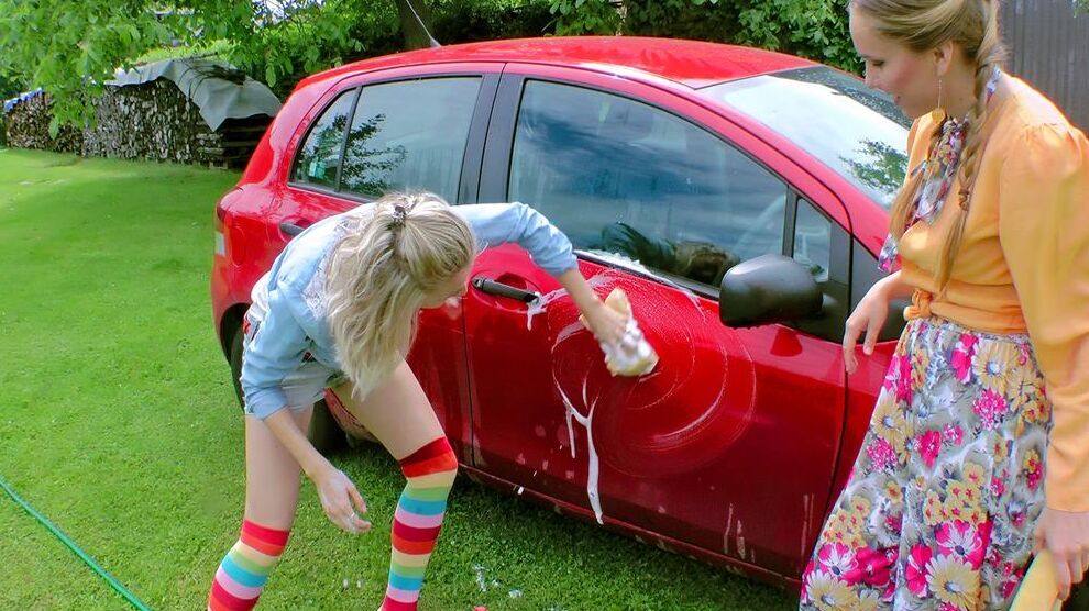 14P Young girls soak each other in a backyard while washing a compact vehicle