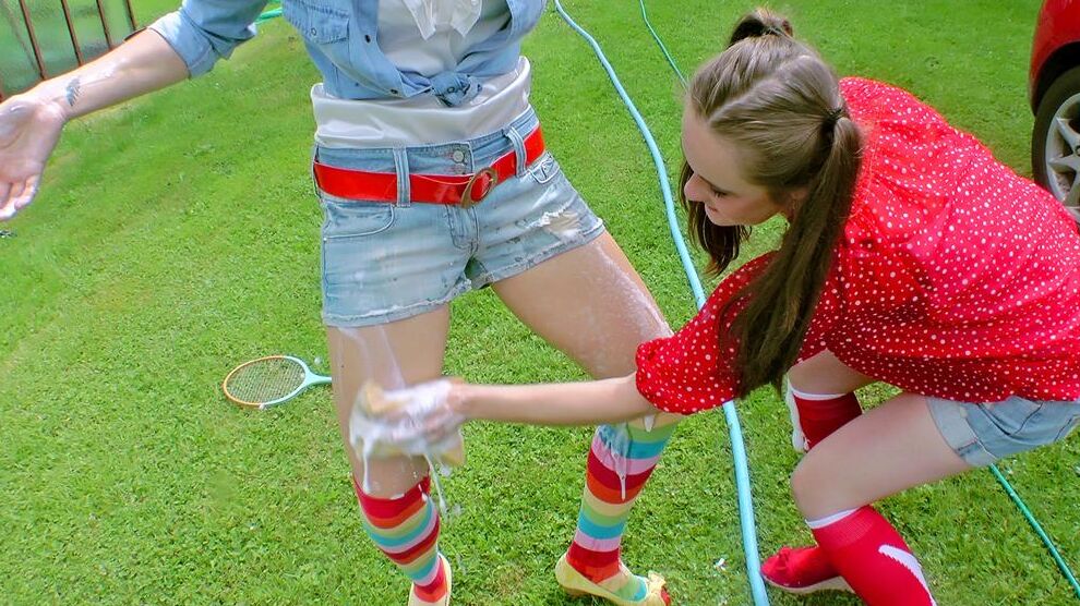 14P Young girls soak each other in a backyard while washing a compact vehicle