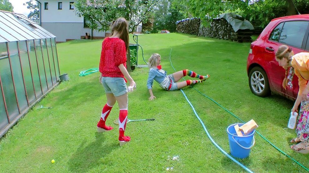 14P Young girls soak each other in a backyard while washing a compact vehicle