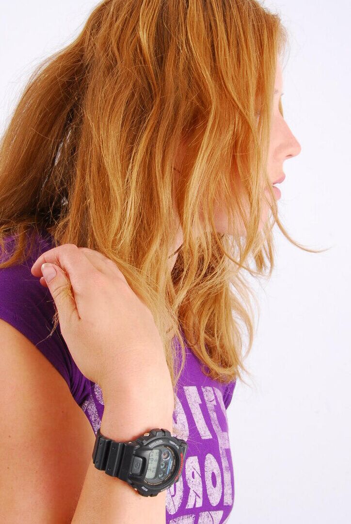 Die 16P natürliche Rothaarige Judy modelliert eine schwarze G-Shock-Uhr, während sie vollständig bekleidet ist