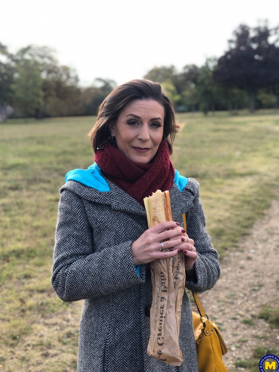 20 fotos La madre francesa Anya muestra sus piernas en medias mientras come un sándwich al aire libre.