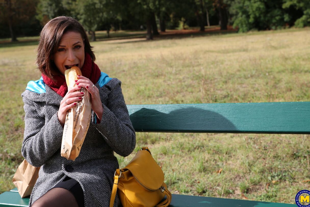 20 fotos La madre francesa Anya muestra sus piernas en medias mientras come un sándwich al aire libre.
