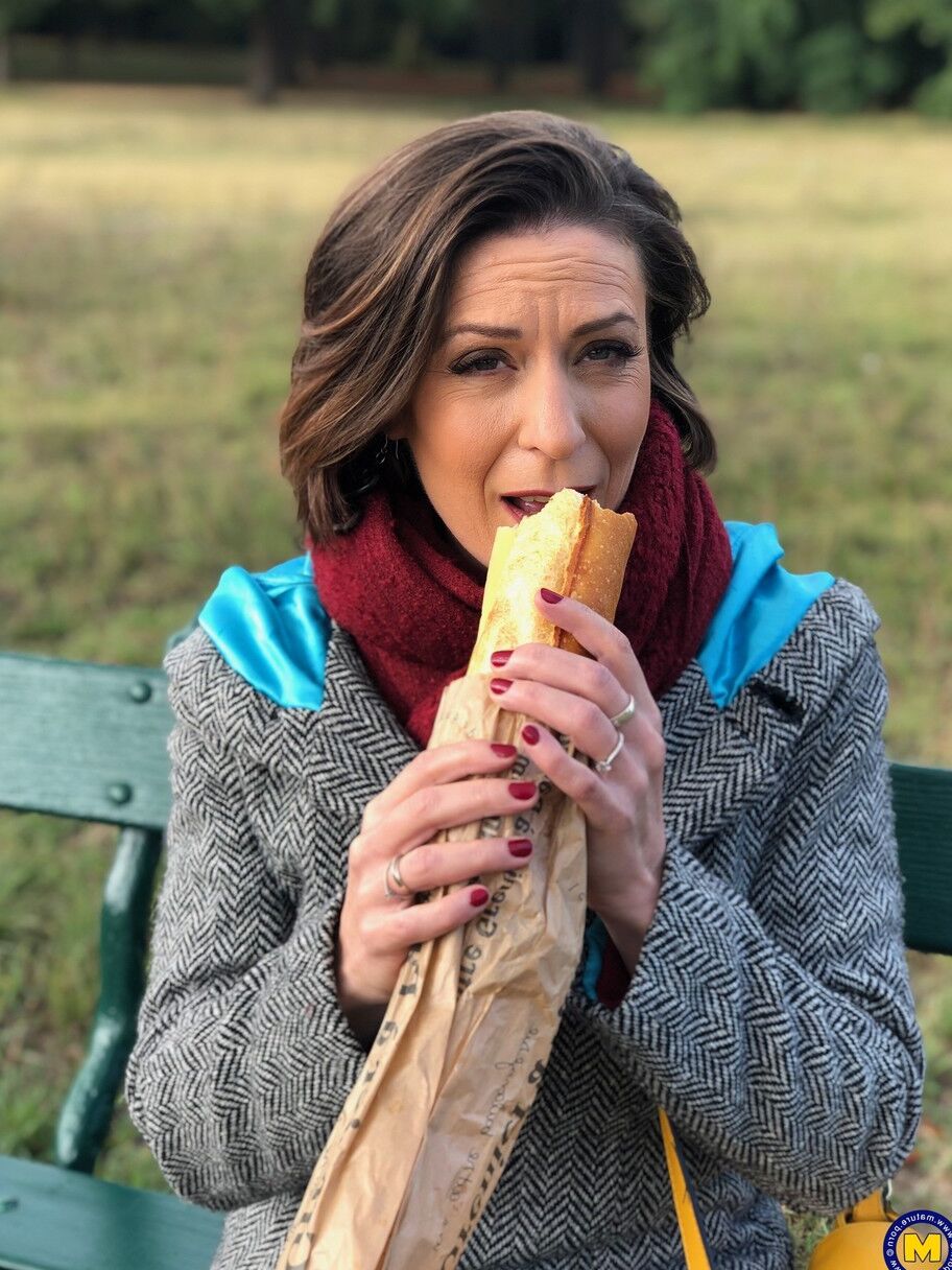 20 fotos La madre francesa Anya muestra sus piernas en medias mientras come un sándwich al aire libre.