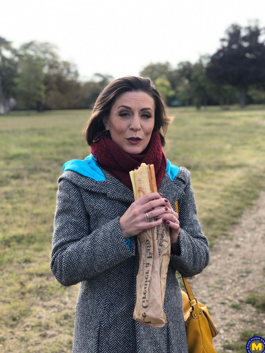 20 fotos La madre francesa Anya muestra sus piernas en medias mientras come un sándwich al aire libre.