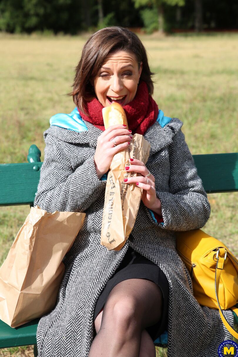 20 fotos La madre francesa Anya muestra sus piernas en medias mientras come un sándwich al aire libre.