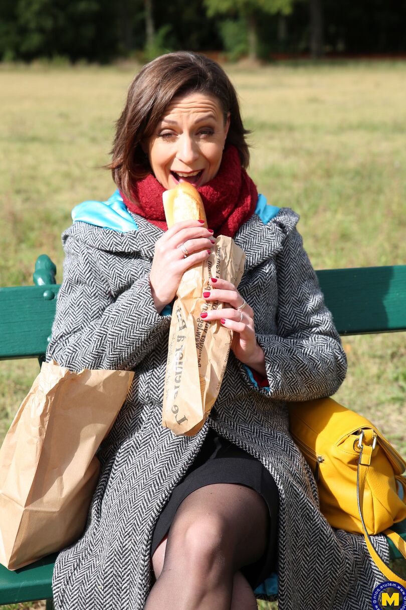 20 fotos La madre francesa Anya muestra sus piernas en medias mientras come un sándwich al aire libre.