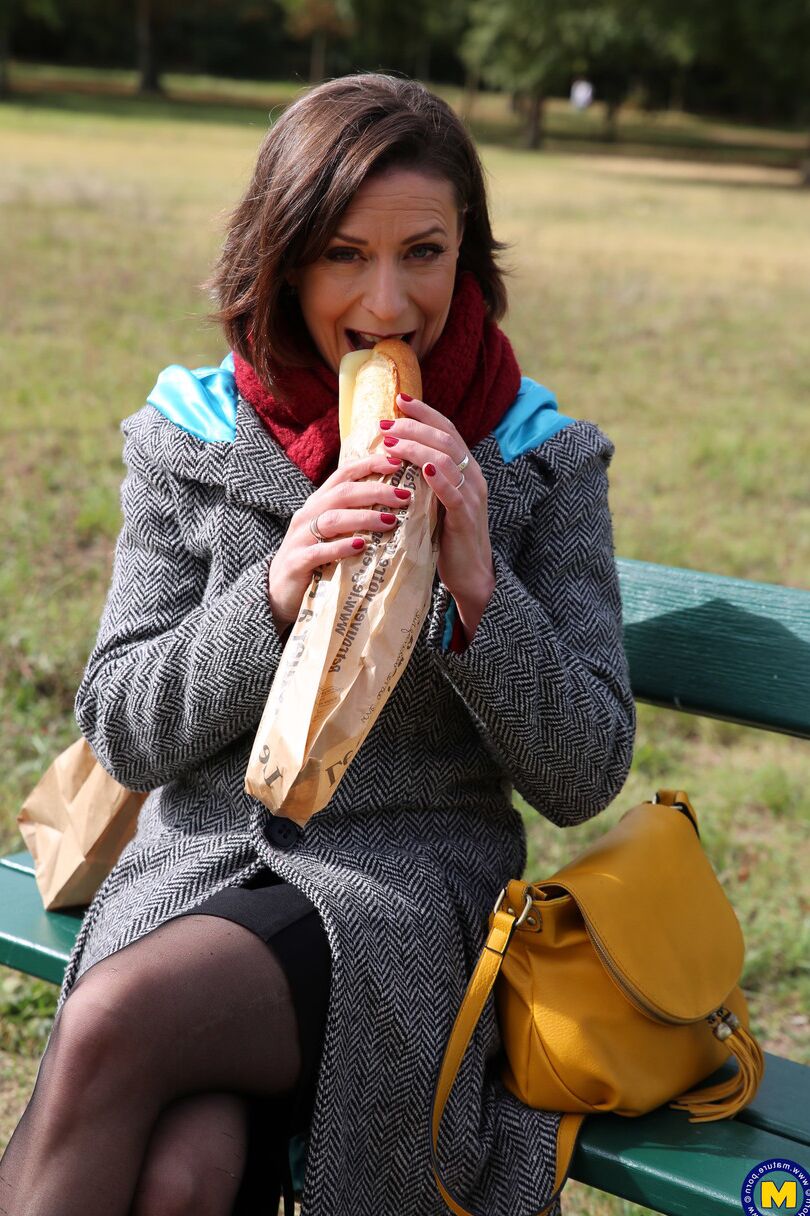 20 fotos La madre francesa Anya muestra sus piernas en medias mientras come un sándwich al aire libre.