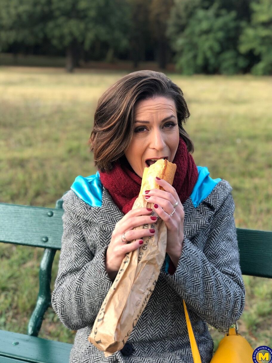 20 fotos La madre francesa Anya muestra sus piernas en medias mientras come un sándwich al aire libre.