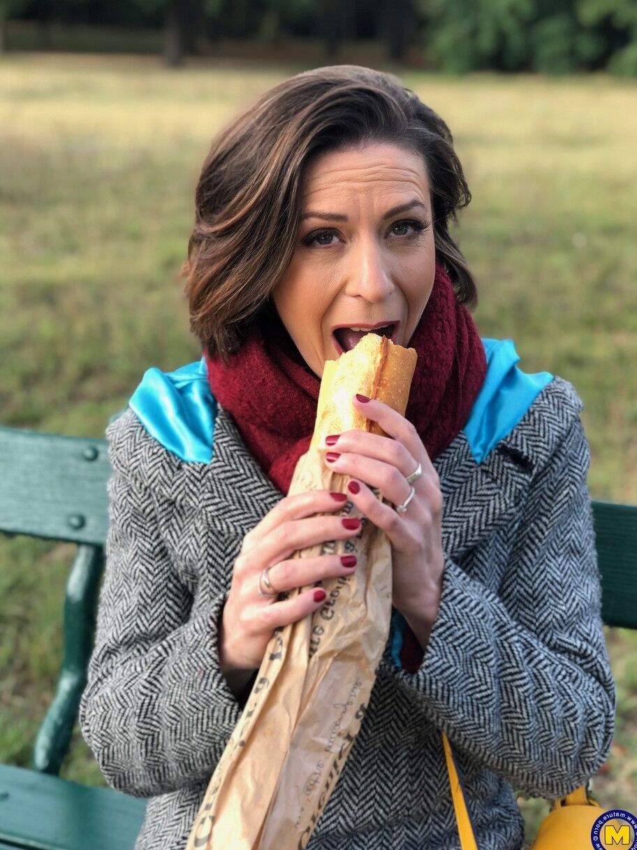 20 fotos La madre francesa Anya muestra sus piernas en medias mientras come un sándwich al aire libre.