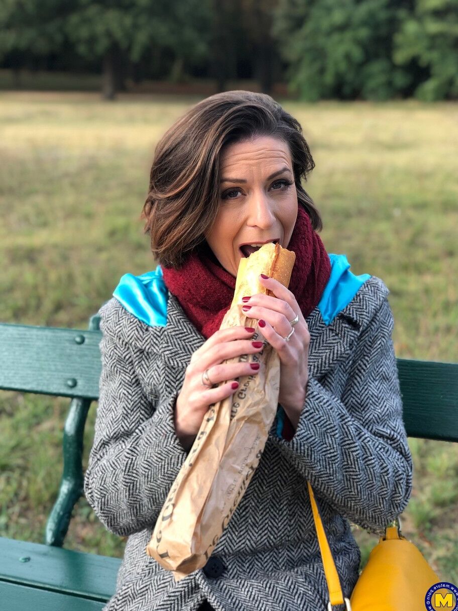 20 fotos La madre francesa Anya muestra sus piernas en medias mientras come un sándwich al aire libre.