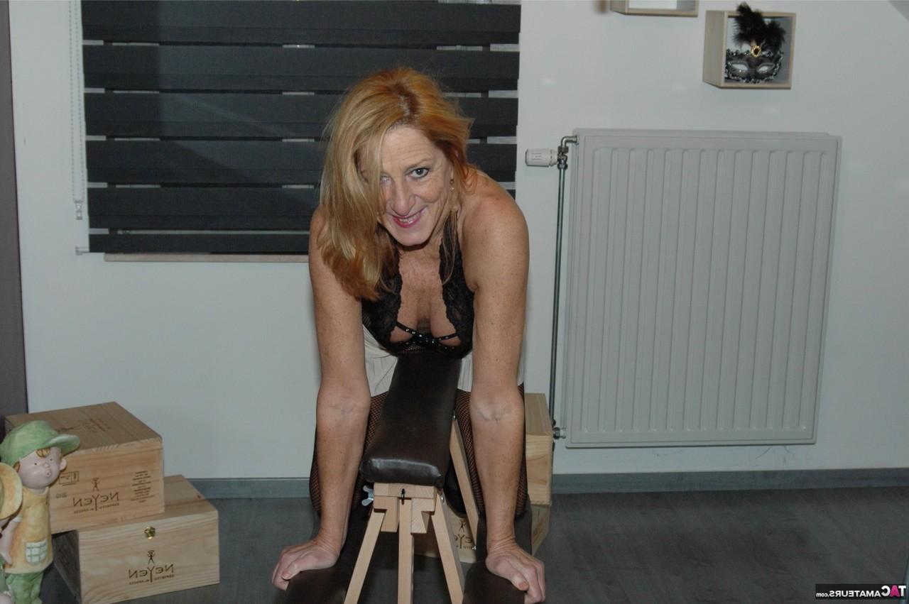 16P La madura Kyras Nylons se monta en un caballo bondage con un body sin entrepierna