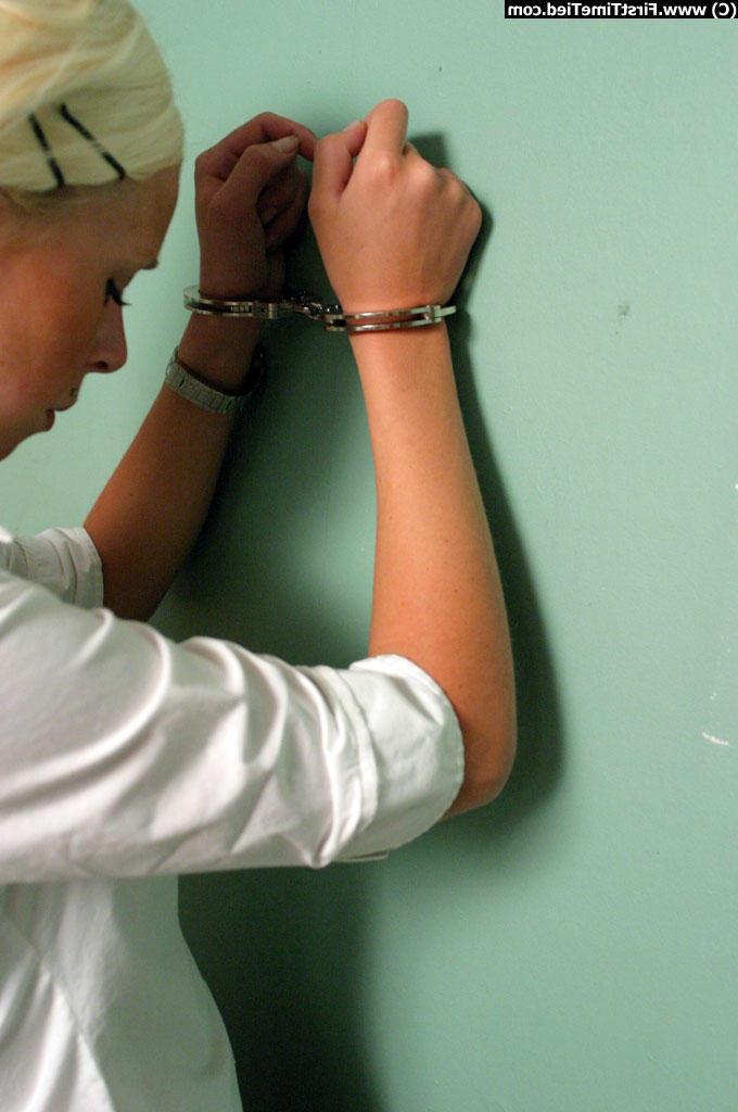 12P Une fille blonde vêtue d'une jupe noire et d'un chemisier blanc est menottée