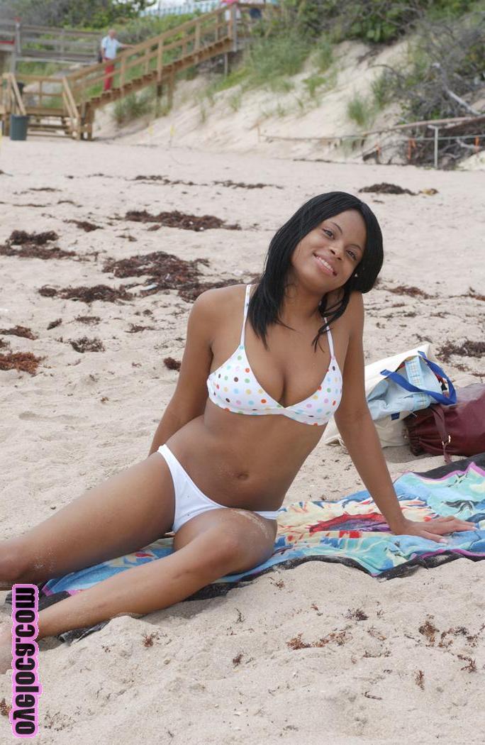 17P La belle jeune ébène Nina Belle aux gros seins se fait bronzer sur la plage en bikini.