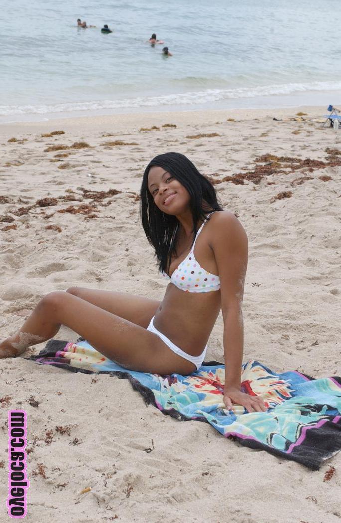17P La belle jeune ébène Nina Belle aux gros seins se fait bronzer sur la plage en bikini.