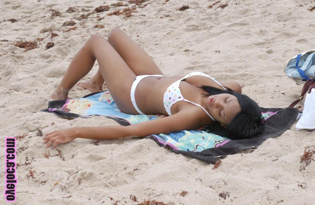 17P La belle jeune ébène Nina Belle aux gros seins se fait bronzer sur la plage en bikini.