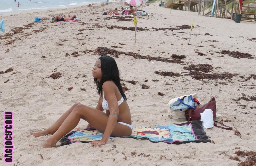 17P La belle jeune ébène Nina Belle aux gros seins se fait bronzer sur la plage en bikini.