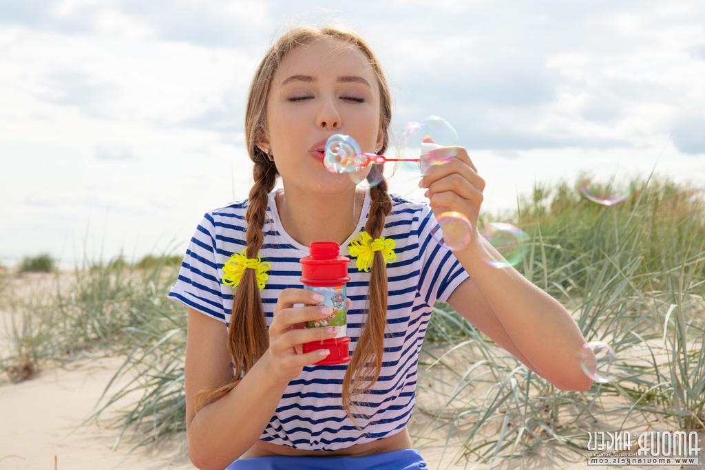 20P La charmante jeune fille Janet souffle des bulles de savon avant de se mettre nue sur une plage.