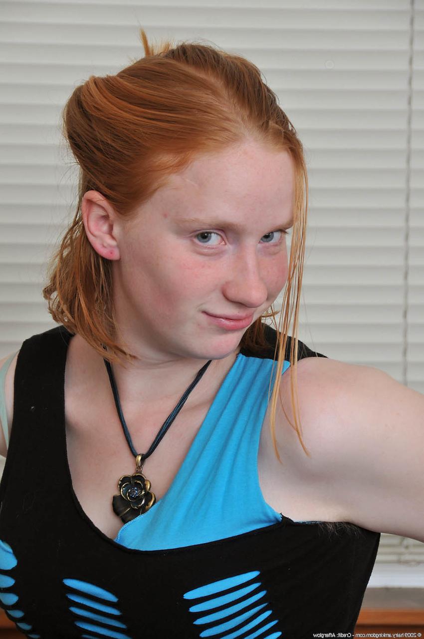 20P Redheaded babe Sandy shows her small teen tits while undressing