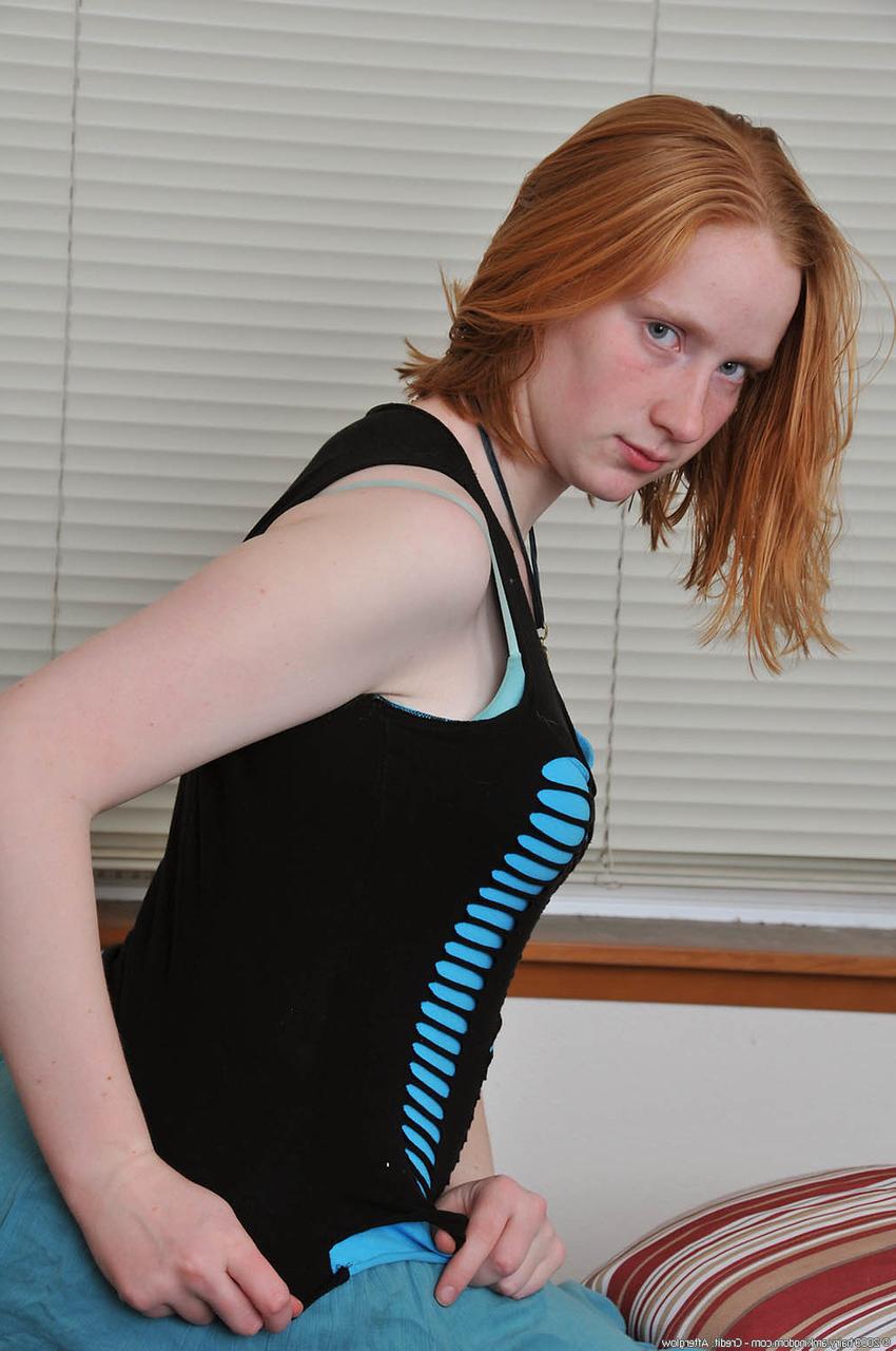 20P Redheaded babe Sandy shows her small teen tits while undressing