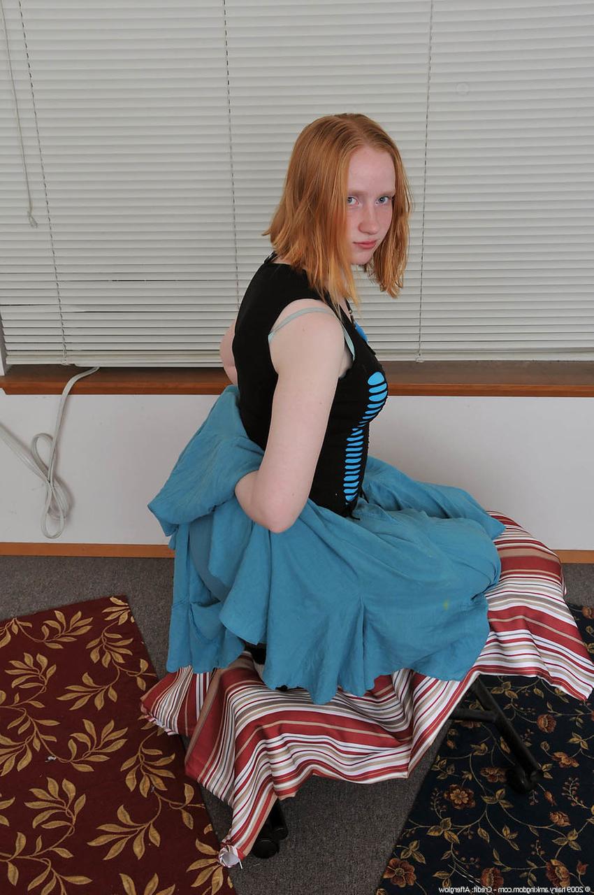 20P Redheaded babe Sandy shows her small teen tits while undressing