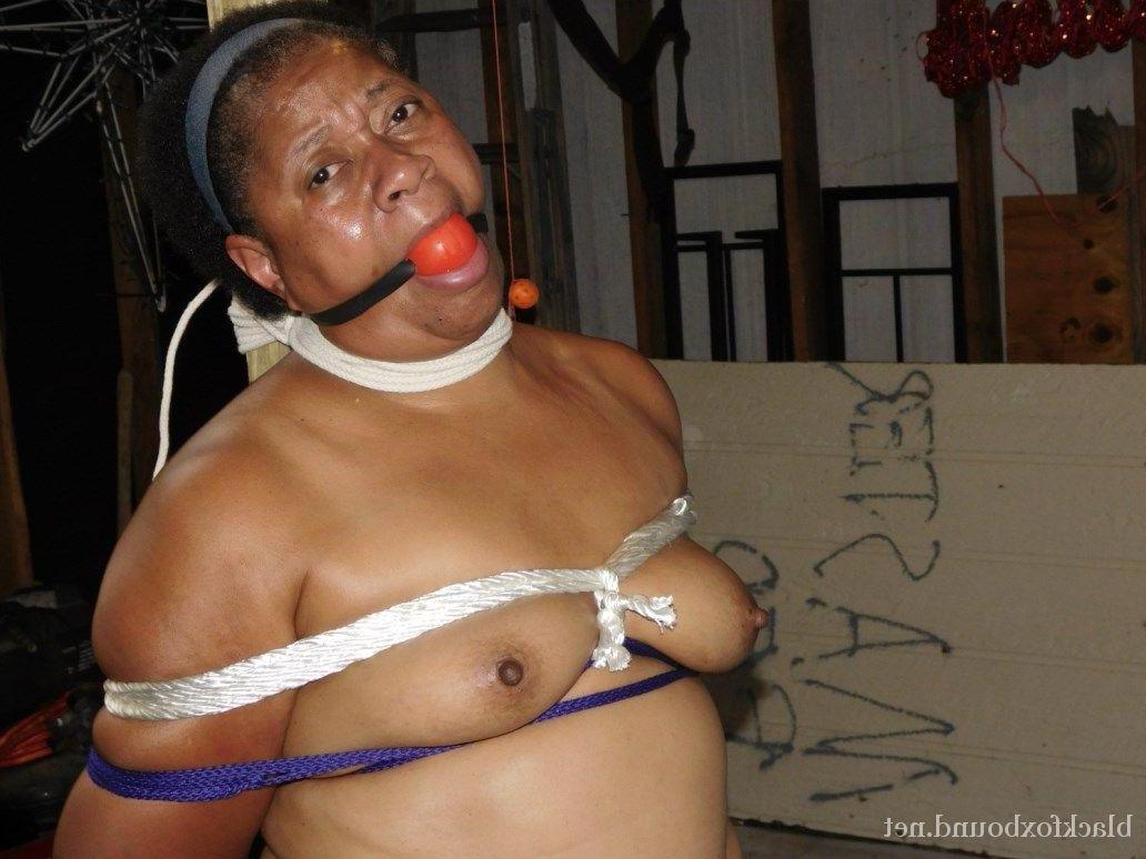 16P O gordo de ébano ostenta uma mordaça de bola e pinças de mamilo enquanto está amarrado a um poste