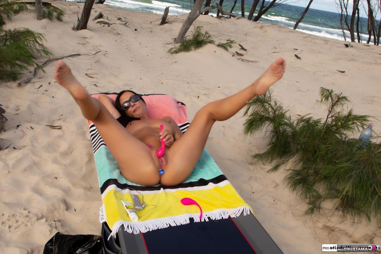 16P A morena MILF Roxeanne usa um plug anal enquanto se masturba na praia