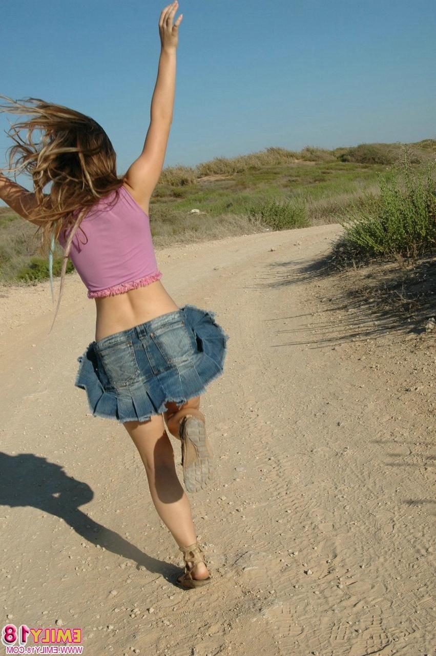 15P Junges Mädchen tobt auf einer unbefestigten Straße und trägt einen Jeans-Minirock und einen Tanga