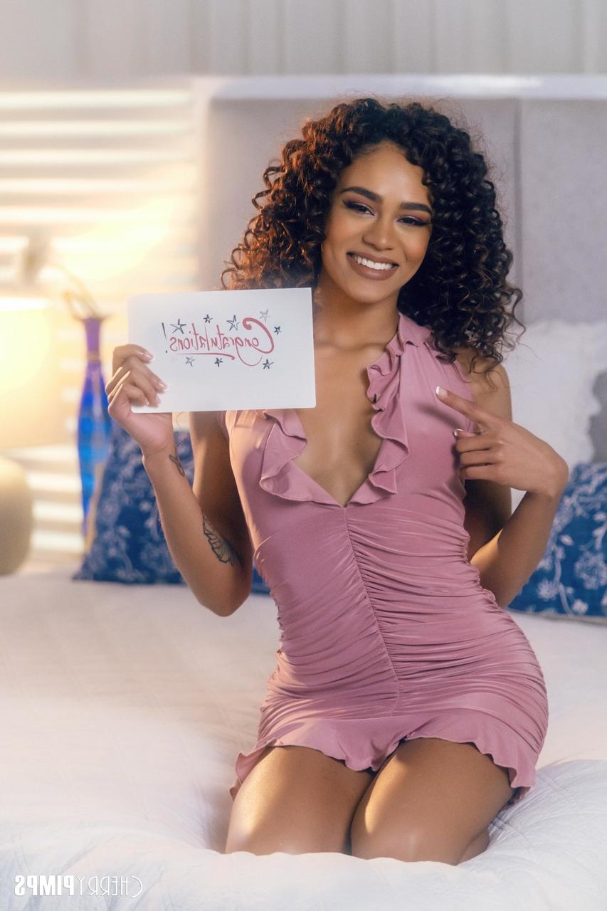 16P Curly-haired ebony Scarlit Scandal posing in her sexy purple dress