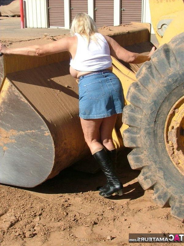 19P Adonna loira madura com excesso de peso se expõe na frente de equipamentos pesados