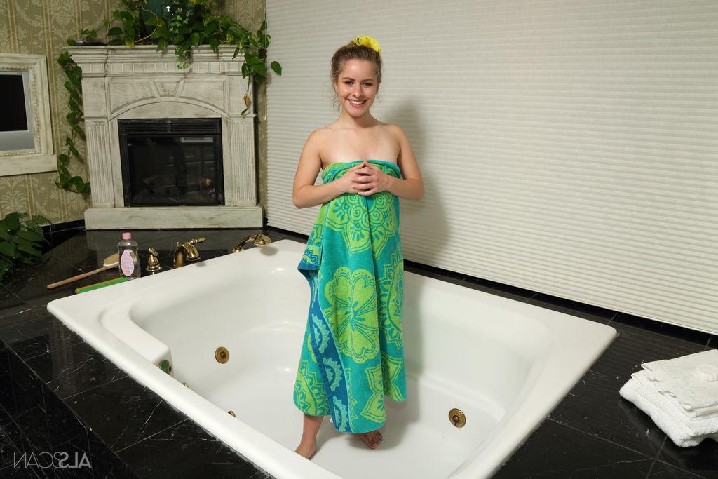 16P La jolie jeune Lilly Ford joue avec sa chatte chauve après s'être aspergée d'huile dans une baignoire.
