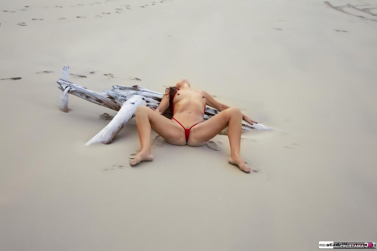 16P Solo model Roxeanne goes topless on a sandy beach in a red thong
